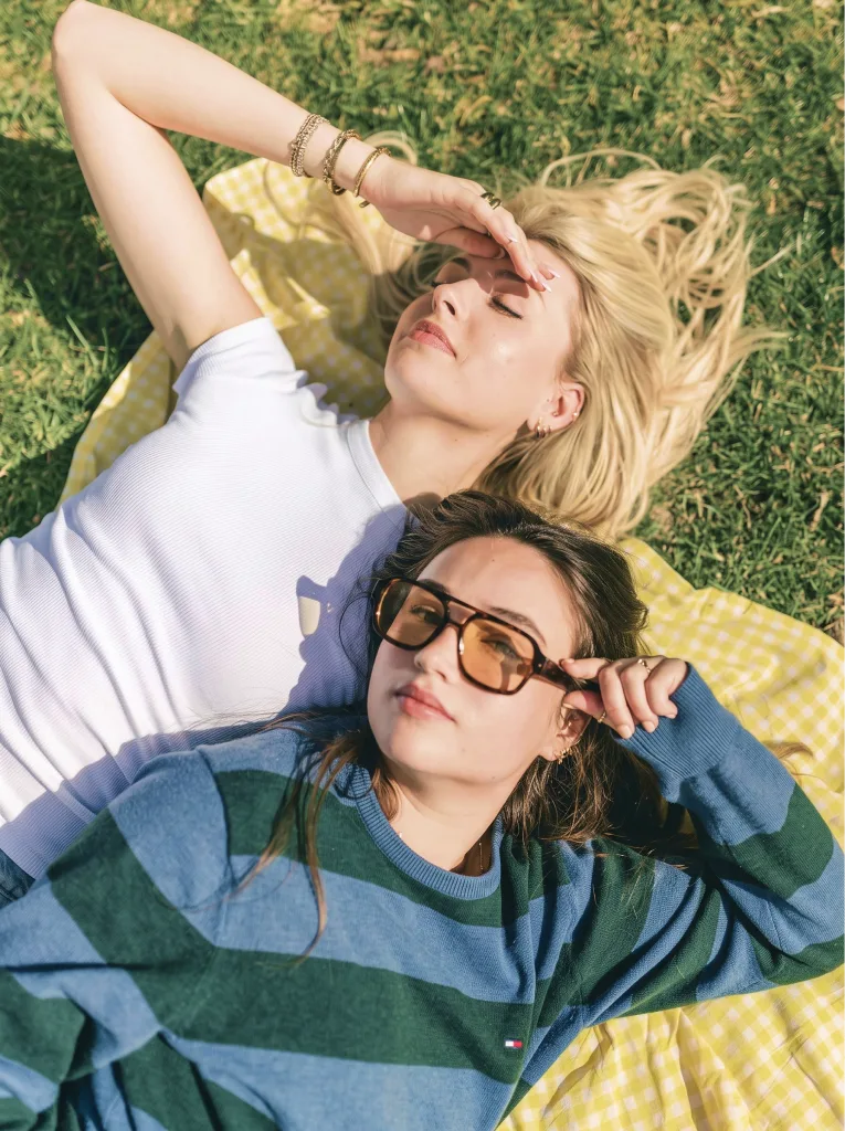 Two models lying on the grass in the sun